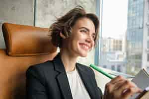 Free photo portrait of woman working in her office businesswoman sitting with her notebook writing and making