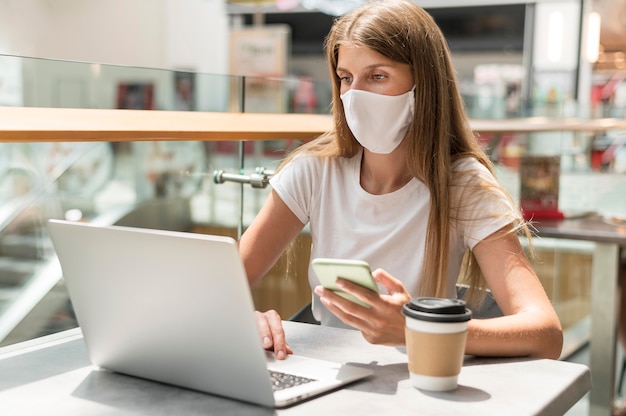 Donna del ritratto che lavora al computer portatile con la maschera