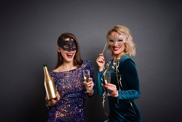 Portrait of women in masks drinking champagne