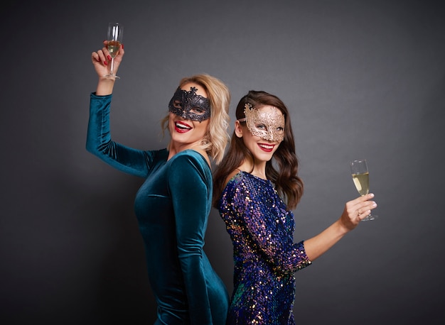 Portrait of women with masks and champagne at the party