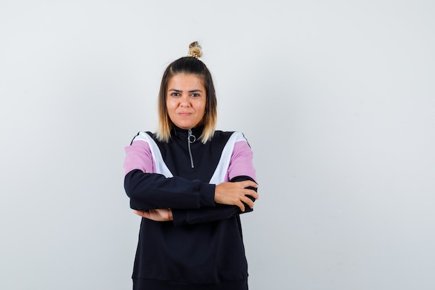 Portrait of wonderful lady holding hands crossed in sweatshirt and looking confident