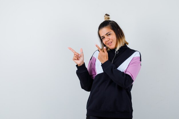 Portrait of wonderful lady pointing to the left side in sweatshirt and looking confident