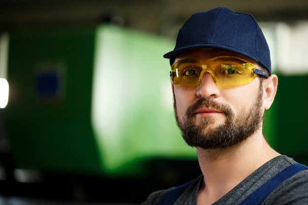 Free photo portrait of worker in overalls, steel factory background.