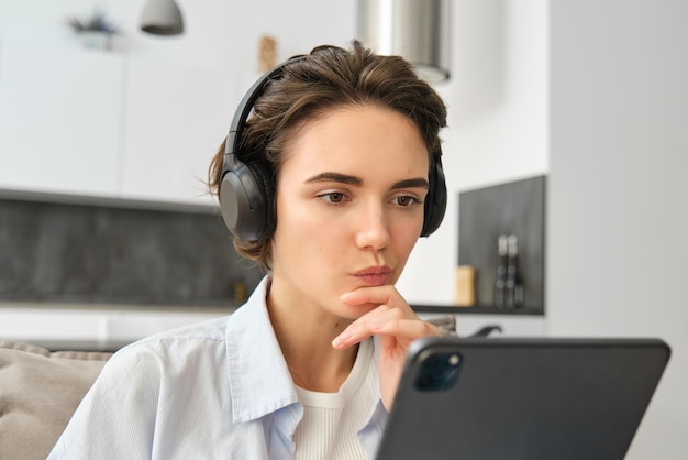 Foto gratuita ritratto di una ragazza che lavora svolge un lavoro online a distanza da casa guarda il tablet e legge