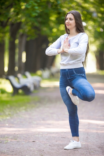 Vrikshasana 포즈에 서 요기 여자의 초상화