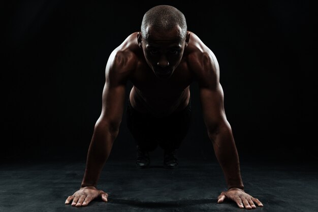Портрет человека афро-американского спорта делает упражнение отжимания