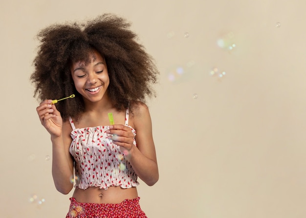 Ritratto di giovane ragazza adorabile in posa mentre gioca con le bolle di sapone