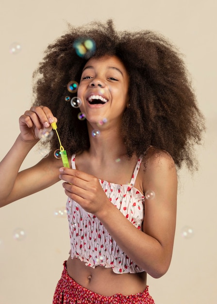 Портрет молодой очаровательной девушки позирует, играя с мыльными пузырями