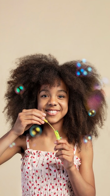 Free photo portrait of young adorable girl posing while playing with soap bubbles