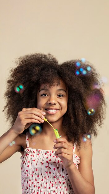 Portrait of young adorable girl posing while playing with soap bubbles