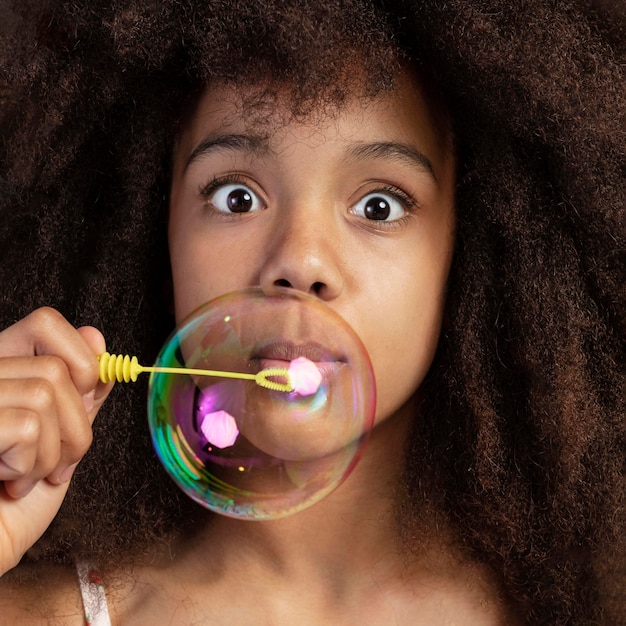 Free photo portrait of young adorable girl posing while playing with soap bubbles