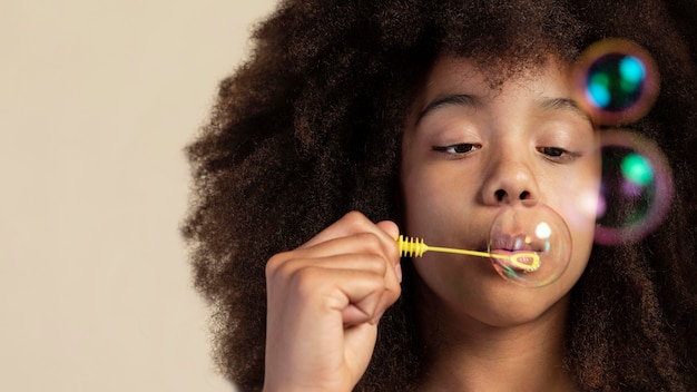 Free photo portrait of young adorable girl posing while playing with soap bubbles