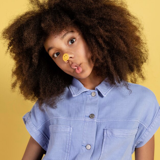 Portrait of young adorable girl posing with emoji stickers on her face