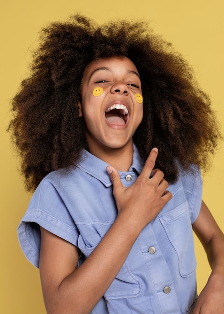 Portrait of young adorable girl posing with emoji stickers on her face