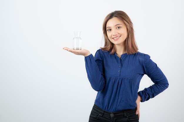 Portrait of young adorable woman holding glass of water on white background. 