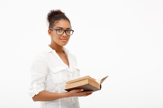 Portrait of young african girl with book over white wall