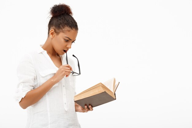 Portrait of young african girl with book over white wall