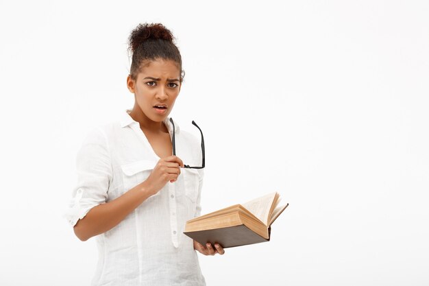 Portrait of young african girl with book over white wall