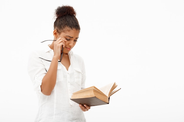 Portrait of young african girl with book over white wall