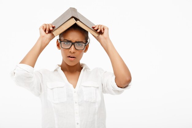 Portrait of young african girl with book over white wall