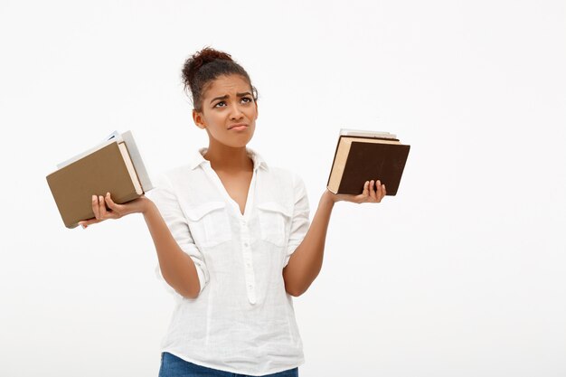 Portrait of young african girl with books over white wall