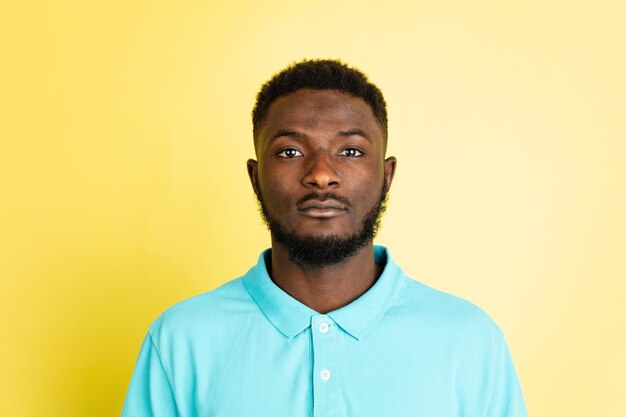 Portrait of young African man isolated over yellow studio background with copyspace