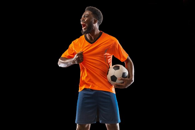 스포츠의 검은 배경 개념에 고립 된 포즈를 취하는 젊은 아프리카 축구 선수의 초상화