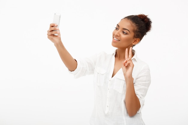 Портрет молодой африканской женщины делая selfie на белом backgrou