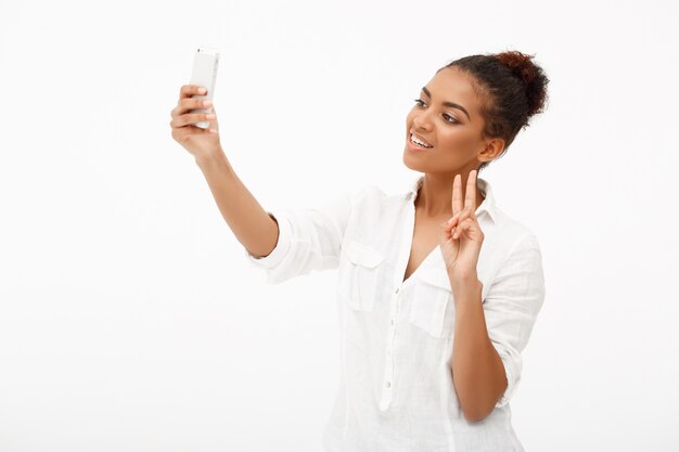 Portrait of young african woman making selfie on white backgrou