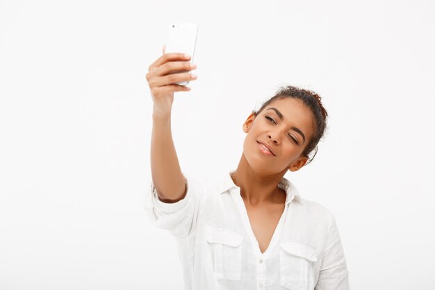 백색 backgrou에 selfie를 만드는 젊은 아프리카 여자의 초상화
