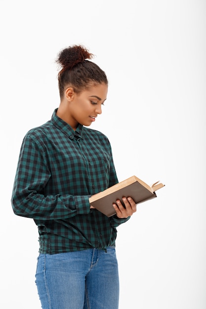 Ritratto di giovane donna africana con il libro su bianco.