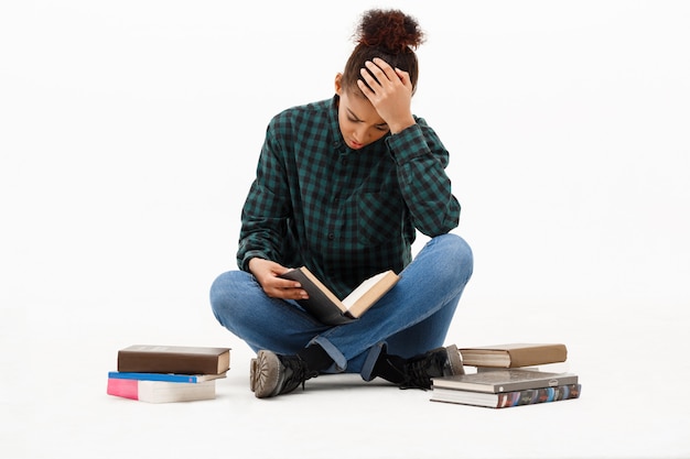 Ritratto di giovane donna africana con i libri su bianco.