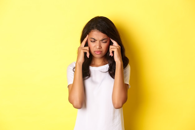 Portrait of young africanamerican female model feeling sick frowning and touching head complaining