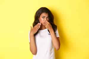 Free photo portrait of young africanamerican girl shut her nose and looking at something with disgusting smell