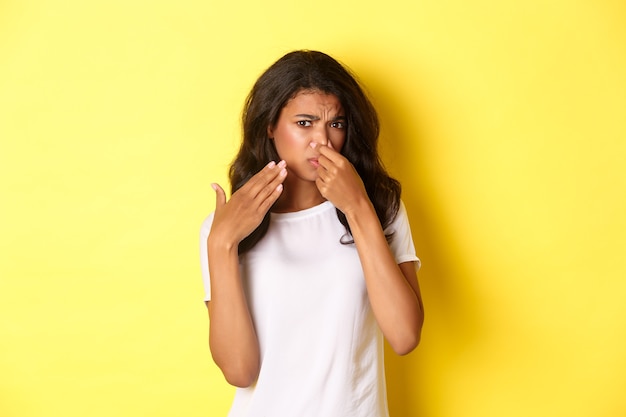 Portrait of young africanamerican girl shut her nose and looking at something with disgusting smell