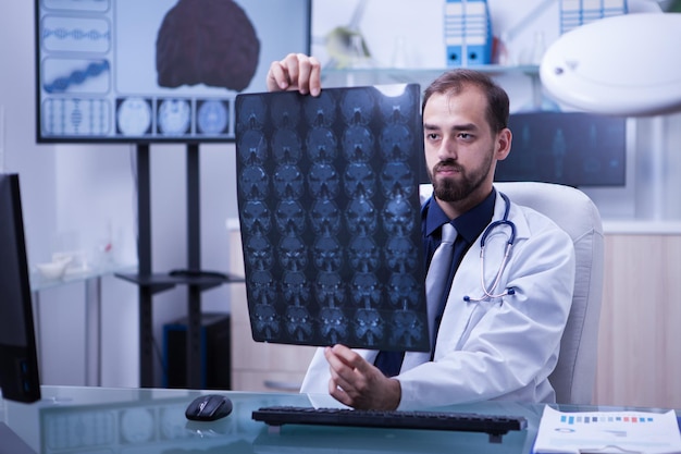 Portrait of young and ambitious doctor examining a brain x ray. doctor holding a brain radiograph.