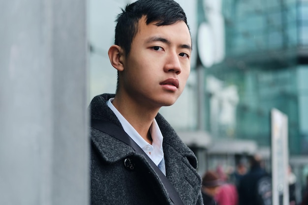 Free photo portrait of young asian businessman confidently looking in camera outdoor