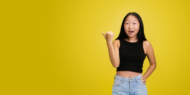 Portrait of young asian girl isolated on yellow studio