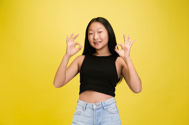 Portrait of young asian girl isolated on yellow