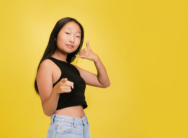 Portrait of young asian girl isolated on yellow