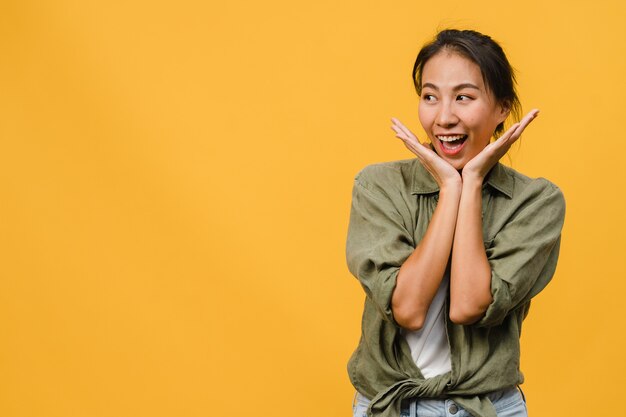 Portrait of young Asian lady with positive expression, smile broadly, dressed in casual clothing over yellow wall. Happy adorable glad woman rejoices success. Facial expression concept.