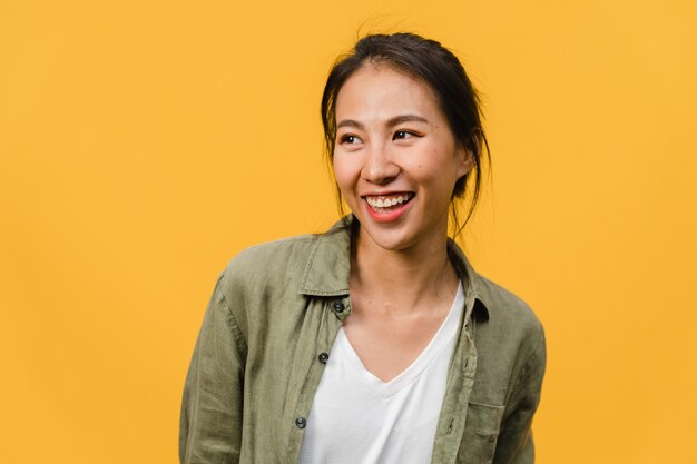 Portrait of young Asian lady with positive expression, smile broadly, dressed in casual clothing over yellow wall. Happy adorable glad woman rejoices success. Facial expression concept.