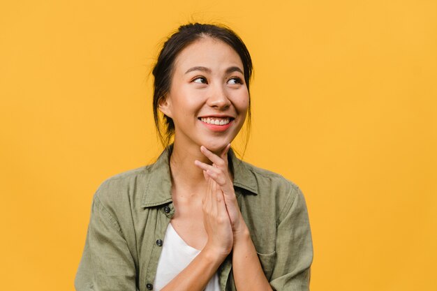 Portrait of young Asian lady with positive expression, smile broadly, dressed in casual clothing over yellow wall. Happy adorable glad woman rejoices success. Facial expression concept.