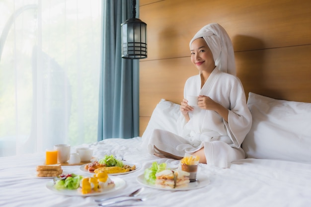 Портрет молодой азиатской женщины на кровати с завтраком в спальне
