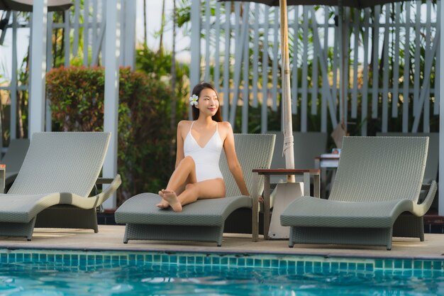 Portrait young asian woman happy smile relax around swimming pool in hotel resort