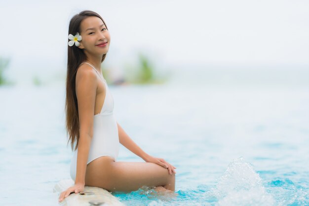 肖像若いアジア女性の幸せな笑顔はホテルリゾートのスイミングプールの周りでリラックスします。