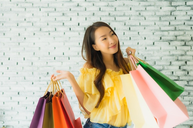 Free photo portrait young asian woman holding colorful shopping bag