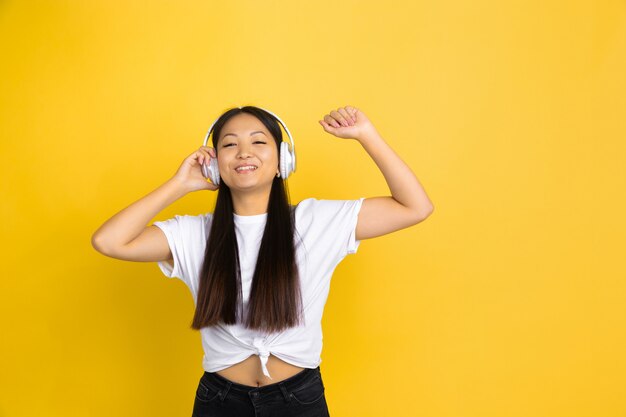 Portrait of young asian woman isolated on yellow wall