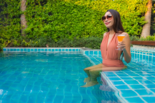 세로 젊은 아시아 여자 호텔 수영장 주위에 행복한 미소를 휴식
