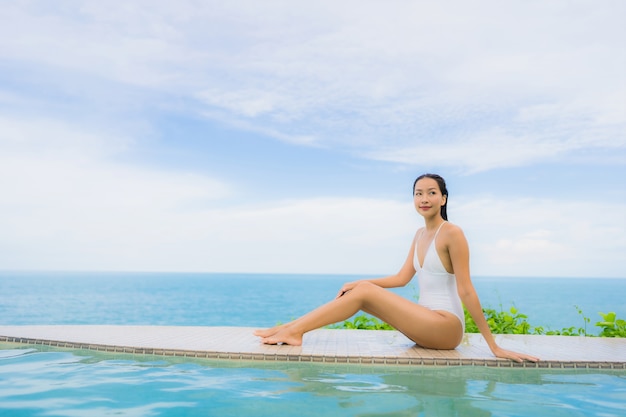 アジアの若い女性の肖像画は、海のオーシャンビューのホテルリゾートの屋外スイミングプールの周り幸せな笑顔をリラックス